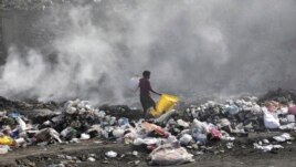 FILE - A woman walks through a landfill looking for salvageable items, in Port-au-Prince, Haiti, Saturday, July 1, 2023. (AP Photo/Odelyn Joseph)