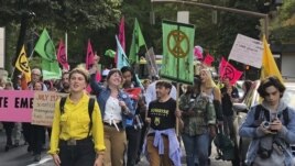 In this photo taken June 21, 2019, people demonstrating to raise awareness of climate change blocked streets in downtown Portland, Ore.