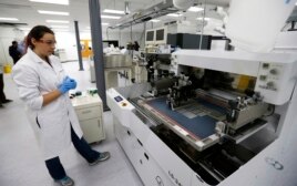 Caitlin Cramer, a PhD student in materials science engineering, demonstrates a machine that can produce electrical circuits and solar cells at the newly opened Washington Clean Energy Testbeds laboratory at the University of Washington.