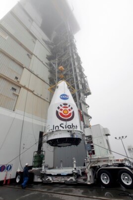 In this April 23, 2018 photo made available by NASA, a crane is used to lift NASA's InSight Mars lander for installation atop a United Launch Alliance Atlas V rocket at Vandenberg Air Force Base in California