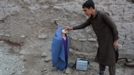 An Afghan health worker administers the polio vaccine to a child during a vaccination campaign on the outskirts of Jalalabad on March 12, 2018.
