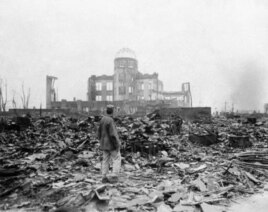 This Sept. 8, 1945 picture shows an allied correspondent standing in the rubble in front of the shell of a building that once was a movie theater in Hiroshima, Japan, a month after the first atomic bomb ever used in warfare was dropped by the U.S.