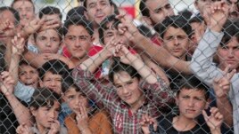 Migrants stand behind a fence at the Nizip refugee camp in Gaziantep province, southeastern Turkey, April 23, 2016.