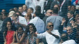 Cuban President Raul Castro, right, cheers next to U.S. President Barack Obama, his wife Michelle, and their daughters Sasha and Malia, at the start of a baseball game between the Tampa Bay Rays and the Cuban national baseball team, in Havana, Cuba, Tuesd