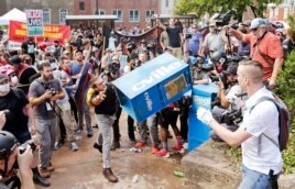 FILE - In this Aug. 12, 2017 file photo, white nationalist demonstrators, right, clash with a counter demonstrator as he throws a newspaper box at the entrance to Lee Park in Charlottesville, Va.