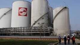 FILE - Officials walk by palm oil storage tanks at Indonesia's Sinar Mas Agro Resources refinery May 3, 2012