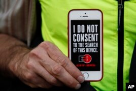 A man holds up his iPhone during a rally in support of data privacy outside an Apple store in San Francisco, Calif., Feb. 23, 2016. Protesters strongly criticized a court order telling Apple to help unlock an encrypted iPhone. (AP Photo/Eric Risberg)
