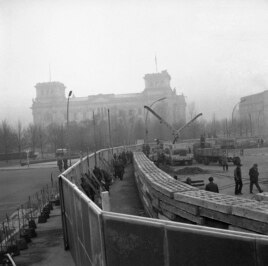 This Nov. 20, 1961 photo shows 12 feet high boards hiding the work as East German troops erect a new concrete wall at the Brandenburg Gate, marking the East-West border in Berlin. In background is the former Reichstag building which is in West Berlin. (AP Photo)