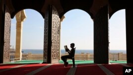 A Palestinian youth reads verses of the Quran, Islam's holy book, during the holy Islamic month of Ramadan at the beach side Mosque in Gaza City, June 9, 2016. (AP Photo/Adel Hana)