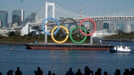 FILE - The Olympic Rings is put back up after they were taken down for repairs ahead of the postponed Tokyo 2020 Olympics in the Odaiba section of Tokyo, Tuesday, Dec. 1, 2020. (AP Photo/Eugene Hoshiko)