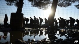 The sun rises as refugees and migrants walk to pass from the northern Greek village of Idomeni to southern Macedonia, Friday, Sept. 11, 2015. The sudden onset of autumn has taken tens of thousands by surprise all along the Balkans route from Greece to Hun