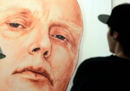 FILE - A man looks at a portrait of ex-spy Andrei Litvinenko by Russian artists Dmitry Vrubel and Viktoria Timofeyeva in the Marat Guelman gallery in Moscow.