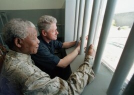 FILE - In this March 27, 1998 file photo, Nelson Mandela and former US president Bill Clinton look to the outside from Mandela's Robben Island prison cell in Cape Town, South Africa.