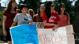 Sonja Breda, 23, right, holds a sign saying 