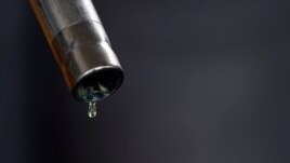 A drop of diesel is seen at the tip of a nozzle after a fuel station customer fills her car's tank in Sint Pieters Leeuw, Dec. 5, 2014. 