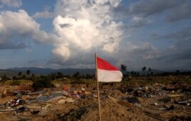 An Indonesian flag flies over the flattened village of Petopo in Palu, Indonesia's Central Sulawesi