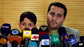 FILE--In this file photo taken on Thursday, July 15, 2010, Shahram Amiri, an Iranian nuclear scientist holds his son Amir Hossein at the Imam Khomeini airport after returning from the United States. Iranian officials said he was executed after being sentenced to death.