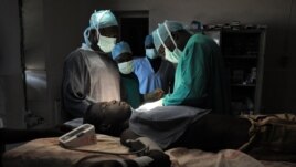 FILE - Evan Atar Adaha performs a surgery on a Sudanese youth at a hospital in Kurmuk region of Sudan's Blue Nile state, Oct. 10, 2011.