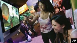 Members of the PMS Clan, a group of professional women gamers, Alexis Hebert, seated, and Felicia Williams play an X-Box game titled 