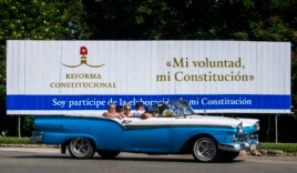 In this Oct. 2, 2018 photo, tourists take a joy ride in a vintage convertible car, past a billboard promoting constitutional reform