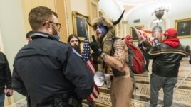 FILE - In this Jan. 6, 2021, file photo supporters of President Donald Trump are confronted by U.S. Capitol Police officers outside the Senate Chamber inside the Capitol in Washington. An Arizona man seen in photos and video of the mob wearing a fur hat w