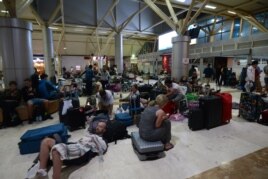 Foreign tourists sleep on the floor as they wait to depart from the Praya Lombok International Airport on the West Nusa Tenggara province on August 6, 2018.