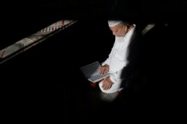 FILE - Abdul Barek Hajji, a Bengali Muslim, reads the Koran while waiting for the Maghrib sunset prayer during Ramadan at the Abu Bakr Mosque in Flushing, New York, May 31, 2017.