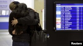 A couple embraces next to a flight information board at Pulkovo airport in St. Petersburg,  Oct. 31, 2015. 