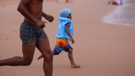 FILE - A child runs as beach-goers enjoy New Year's Day in the rain, on the beach in Durban, South Africa January 1, 2024. (REUTERS/Rogan Ward)