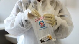 FILE - A health worker holds a COVID-19 sample collection kit of a vaccine trial volunteer, after a test for the coronavirus disease, at the Wits RHI Shandukani Research Centre in Johannesburg, South Africa, Aug. 27, 2020.